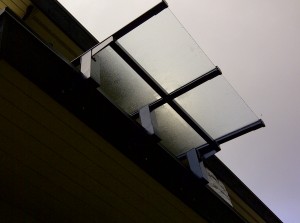 brand new glass canopy system installed into a residential burnaby home. Clear glass canopy installation with aluminum frame. black aluminum glass canopy.