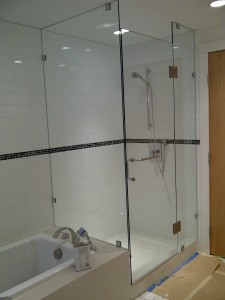 Custom bathroom glass shower walls and shower door system. Thick clear tempered glass walls and glass doors with elegant shower door hinges along with shower door handles, glass wall clamps makes the stand up shower a feature piece to look at for this bathroom.