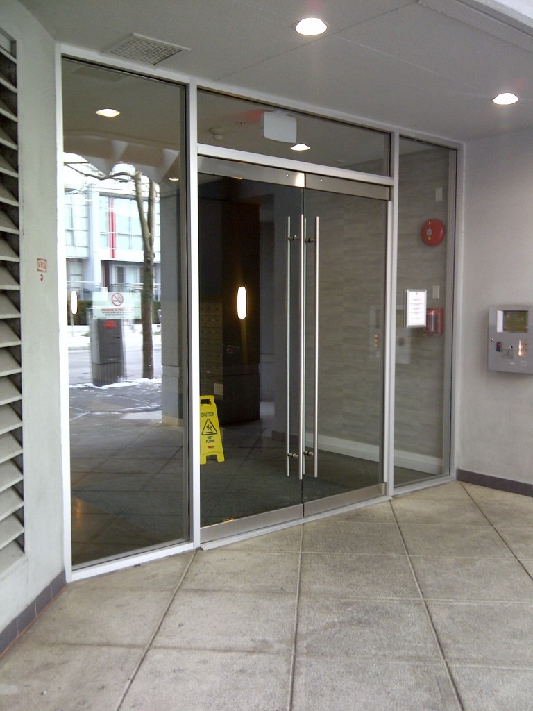 Entrance glass doors supply and installation for a hi rise apartment condo building located in Vancouver downtown. Clear safety tempered glass doors with heavy commercial grade hardware provides a beautiful bright entry, while the commercial grade hardware such as the ladder pull handles, heavy duty door rails, and electric strike system that works with the existing building's intercom system.