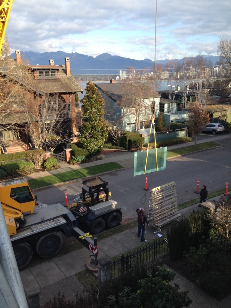 Large heavy skylights and walkable glass panels craned and lifted onto a residential home roof for installation. Skylights and walkable glass panels had been engineered to be sturdy enough for walking on.
